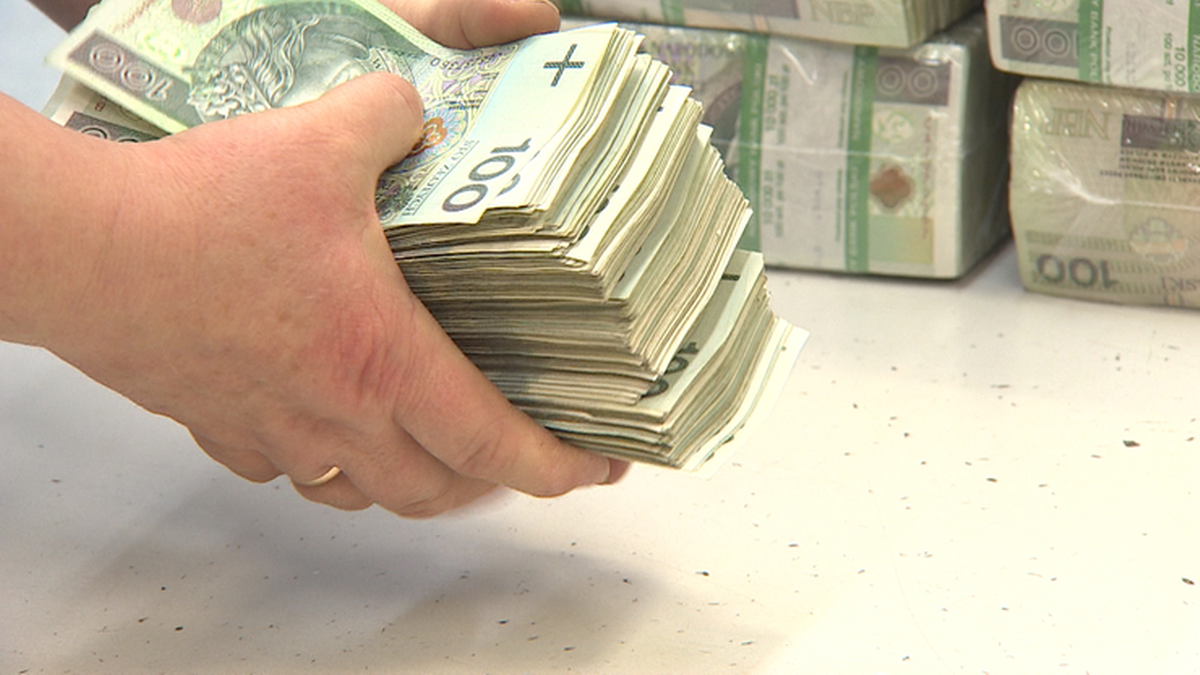 Dłonie trzymające dużą stertę banknot&oacute;w 100-złotowych.