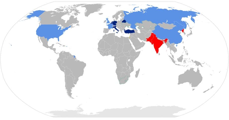 Globalna mapa kraj&oacute;w z dostępem do broni atomowej. Niebieski - państwa posiadające broń jądrową zgodnie z ustaleniami międzynarodowymi (Chiny, Francja, Rosja, Wielka Brytania, Stany Zjednoczone), Granatowy - Państwa NATO lub CSTO objęte polityką udostępniania broni jądrowej (Belgia, Niemcy, Holandia, Włochy, Turcja, Białoruś), Czerwony - Inne państwa posiadające broń jądrową (Indie, Pakistan, Korea P&oacute;łnocna), Pomarańczowy - Państwa nieoficjalnie będące posiadaczami broni jądrowej (Izrael)