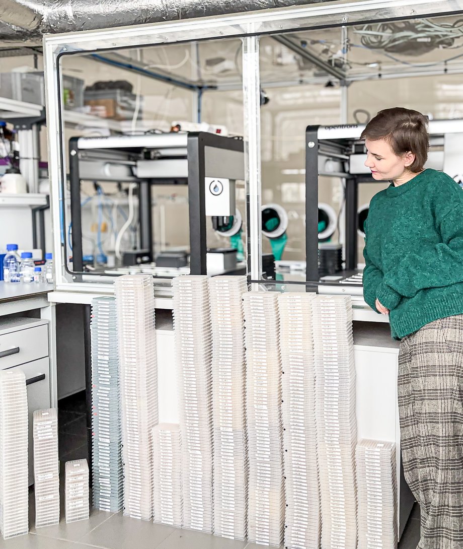 Kierownik Katedry Chemii stoi obok stos&oacute;w płytek, kt&oacute;re reprezentują serię badań przesiewowych obejmującą ponad 60 tys. reakcji, przeprowadzoną na początku tego roku.